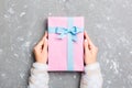 Flat lay of woman hands holding gift wrapped and decorated with bow on gray cement background with copy space. Christmas and Royalty Free Stock Photo