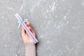 Flat lay of woman hands holding gift wrapped and decorated with bow on gray cement wooden background with copy space. Christmas Royalty Free Stock Photo