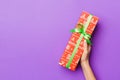 Flat lay of woman hands holding gift wrapped and decorated with bow on purple background with copy space. Christmas and holiday Royalty Free Stock Photo