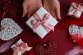 Flat lay of woman hands holding present with box decorated with pink ribbon on red background. Happy valentines day. Christmas Royalty Free Stock Photo