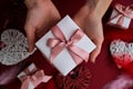 Flat lay of woman hands holding present with box decorated with pink ribbon on red background. Happy valentines day. Christmas Royalty Free Stock Photo