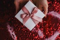 Flat lay of woman hands holding present with box decorated with pink ribbon on red background. Happy valentines day. Christmas Royalty Free Stock Photo