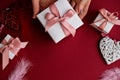 Flat lay of woman hands holding present with box decorated with pink ribbon on red background. Happy valentines day. Christmas Royalty Free Stock Photo