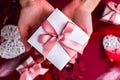 Flat lay of woman hands holding present with box decorated with pink ribbon on red background. Happy valentines day. Christmas Royalty Free Stock Photo