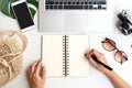 Flat lay of woman hands writing on notebook with travel accessories and laptop on desk. Summer, holiday, work and planning travel Royalty Free Stock Photo