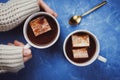 Flat lay of woman`s hands in sweater and two cups of cocoa or hot chocolate