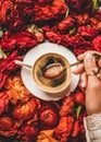 Womans hand holding spoon of espresso coffee over red flowers Royalty Free Stock Photo