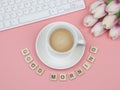 Flat lay of wooden letter around coffee cup  on pink background with computer keyboard and tulip flower bouquet Royalty Free Stock Photo