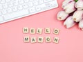 Flat lay of wooden letter HELLO MARCH on pink background with computer keyboard and purple-white tulip bouquet decoration Royalty Free Stock Photo