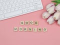 Flat lay of wooden letter on pink background with computer keyboard and tulip flower bouquet Royalty Free Stock Photo