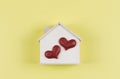 flat lay of wooden model house with two red glitter hearts on yellow background. dream house , home of love, strong relationship Royalty Free Stock Photo