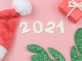 Flat lay of wooden number 2021 on pink background with Christmas hat, green reindeer horn and red gift box. Happy new year 2021 Royalty Free Stock Photo