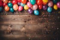 Flat lay of wooden planks with copy space surrounded by colorful party balloons, candy and confetti