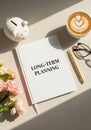 Lifestyle Workspace Flat Lay with \'LONG-TERM PLANNING\' Notebook, Gold Pen, Latte, Eyeglasses & Hydrangea â Minimalist Concept Royalty Free Stock Photo