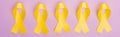 Flat lay with yellow awareness ribbons on violet background, panoramic shot, international childhood cancer day concept.