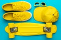 Flat lay of yellow baseball cap, sunglasses, sneakers, mini cruiser skateboard Royalty Free Stock Photo