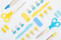 Flat lay of yellow and blue erasers, pens, scissors, compasses and paper clips isolated on white .