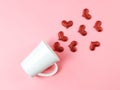 Flat layout image of of red glitter hearts splash out from white coffee cup on pink background Royalty Free Stock Photo