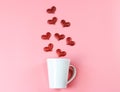 Flat layout image of of red glitter hearts splash out from white coffee cup on pink background Royalty Free Stock Photo
