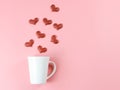 Flat layout image of of red glitter hearts splash out from white coffee cup on pink background Royalty Free Stock Photo