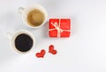 Red  gift box , two red glitter hearts and two cups of coffee on white background. Valentine`s day concept Royalty Free Stock Photo