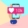 flat minimal hand holding mobile phone with new pink ten chiliad heart like social media icon with shadow on pastel colored blue Royalty Free Stock Photo