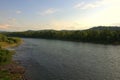 The flat shore of a calm wide river flowing through the forest