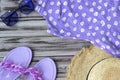 Flat shot of women's summer purple clothes on a wooden background: hat, dress, glasses, trendy slippers.