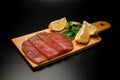 Flat slices of tuna fillet, lemon wedges and seaweed with sesame lie on a wooden board Royalty Free Stock Photo