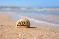 A flat stone with the inscription 2022 stands on the seashore. New Year 2022.