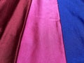 Flat surface of maroon, pink and blue shiny fabric