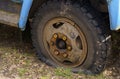 A flat tire of an old fragment of a rusty abandoned broken truck.