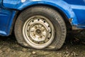 Flat tire part of an abandoned blue car parked in garden photo taken in Depok Indonesia