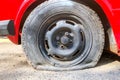 Flat tire of red car on the road waiting for repair. Flat tyre on road. Car tire leak because of nail pounding Royalty Free Stock Photo