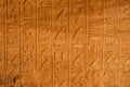 Flat view of a wall covered in ancient egyptian hieroglyphs in a temple in egypt. Many different ancient symbols explain the story