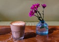 Flat-white australian coffee on worn tabletop with red flowers in blue bottle Royalty Free Stock Photo