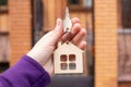 Flat wooden house shaped keychain with a key in hand Royalty Free Stock Photo