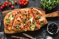 Flatbread pizza garnished with fresh arugula on wooden pizza board, top view