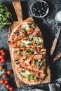 Flatbread pizza garnished with fresh arugula on wooden pizza board, top view Royalty Free Stock Photo