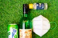 Flatlay of alcohol liquor bottles on grass with a mask and sanitizer showing the home delivery and purchase of alcohol