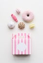 Flatlay of amigurumi toy sweets. Knitted cakes, candies and donuts with pink box on white background Royalty Free Stock Photo