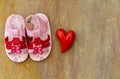 Flatlay with baby sandal shoes and a heart on wooden background Royalty Free Stock Photo