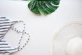 Flatlay bikini, hat, sunglasses, starfish, green leaf of plum on white background.