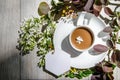 Flatlay with an coffee cup on a saucer with mockup an empty white card framed by branches of burgundy and green leaves Royalty Free Stock Photo