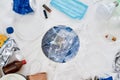 Flatlay composition with different waste, garbage types and paper model of Earth under it in the center over white Royalty Free Stock Photo