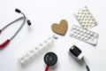 Flatlay composition of medical equipment with wooden heart on white background. Concept of diagnosis, treatment, hospital, patient