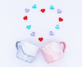 Flatlay composition. Two marble cups in pink and gray color and red, blue and lilac glass hearts laid out in the shape Royalty Free Stock Photo