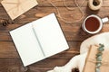 Flatlay cozy winter or Christmas desk table with book, cup of tea, craft paper envelope, rope, gift box, wool sweater on wooden