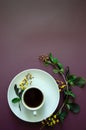 Flatlay A cup of coffee and on a round saucer lies a twig with small yellow flowers and leaves at the bottom Royalty Free Stock Photo