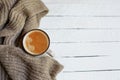 Flatlay with cup of coffee in scarf on white wooden background, autumn or winter concept Royalty Free Stock Photo